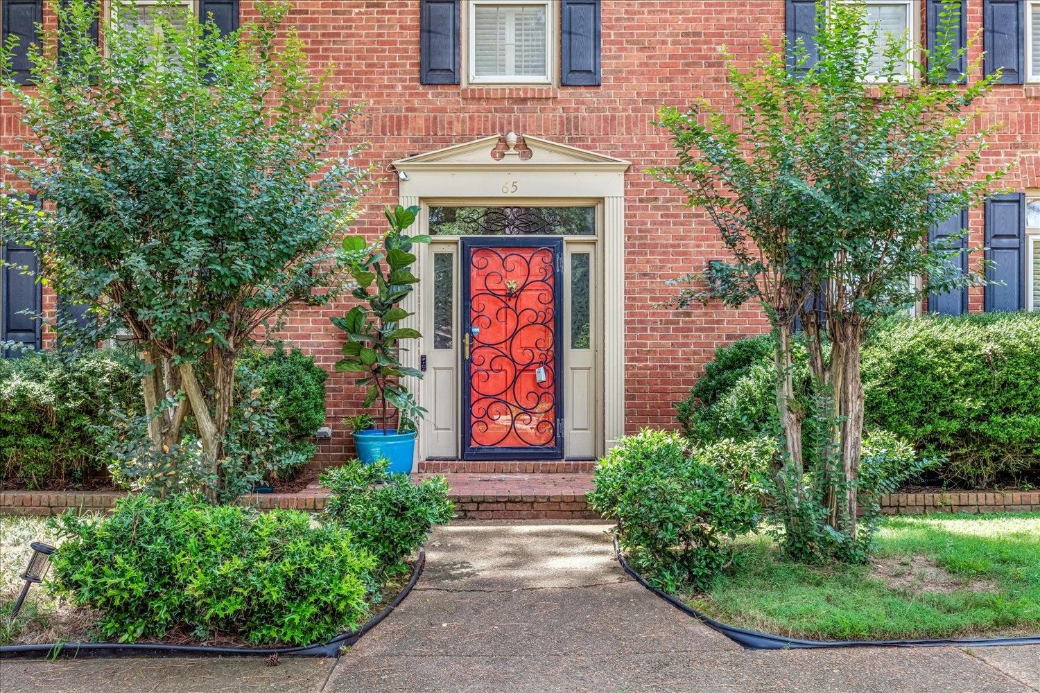 65 Summer Grove Road Memphis, TN 38018 - Photo 5 of 38 Red brick exterior with black shutters, white trim, and a red entry door with wrought iron detailing