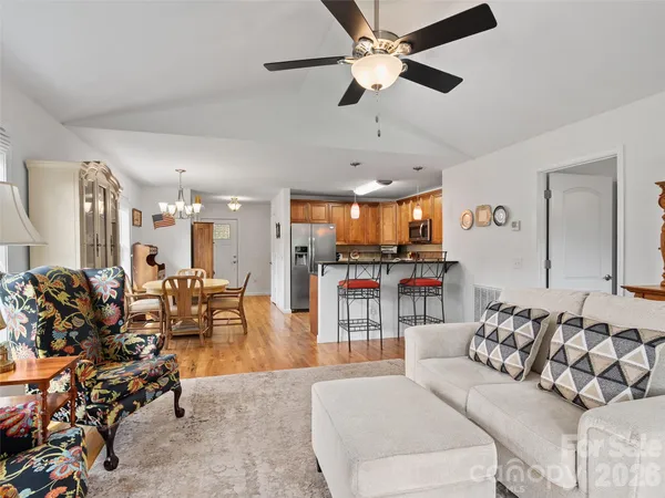 a living room with furniture kitchen view and a wooden floor