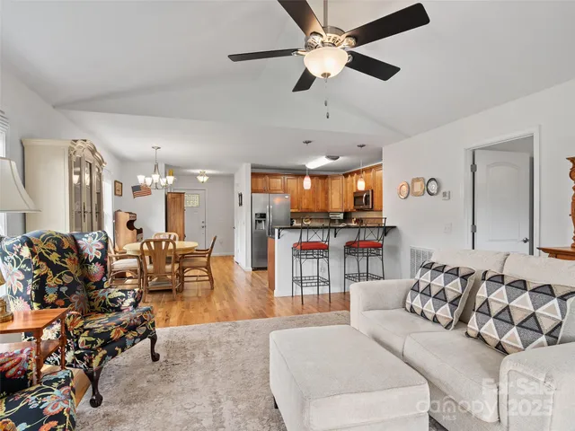 a living room with furniture kitchen view and a wooden floor