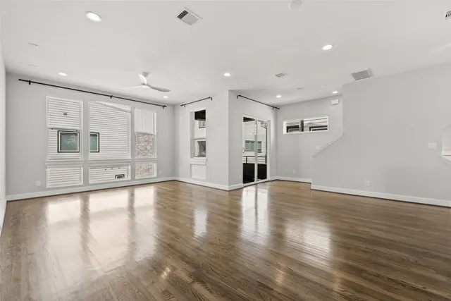 a view of an empty room with window and wooden floor