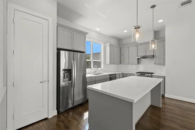 a kitchen with a refrigerator a sink and wooden floor