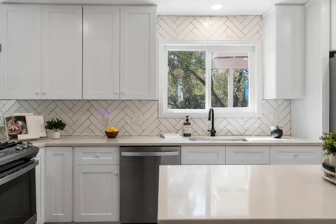 a kitchen with granite countertop a sink and a white wooden cabinets