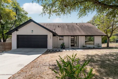 a front view of a house with a garden and trees