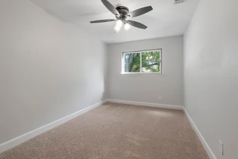 an empty room with a window and a fan