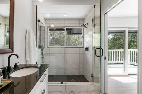 a bathroom with a granite countertop sink a mirror a vanity and a shower