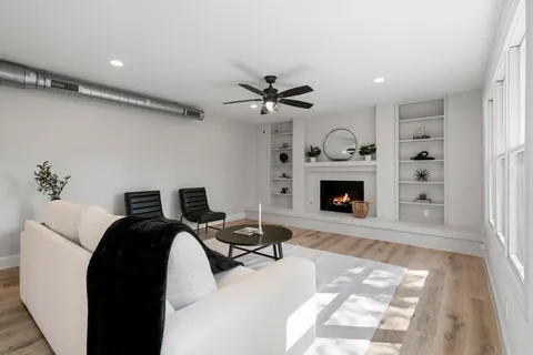 a living room with furniture a fireplace and a ceiling fan