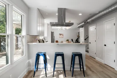 a kitchen with stainless steel appliances granite countertop a table chairs sink and cabinets