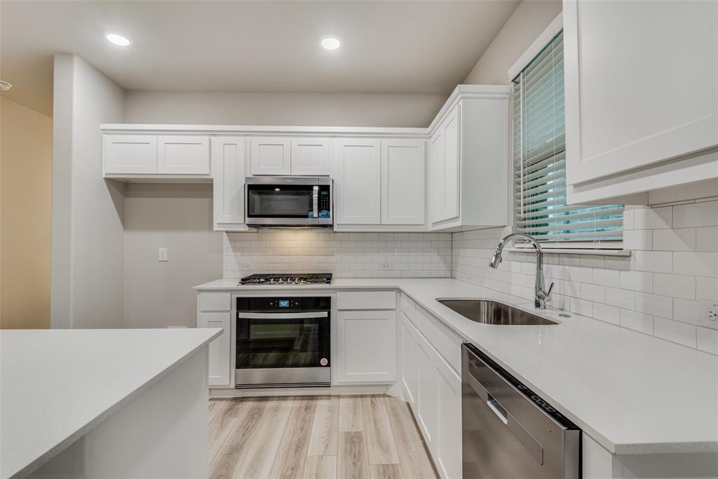 2544 Rambling Road Celina, TX 75009 - Photo 9 of 25 Kitchen with light hardwood / wood-style floors, tasteful backsplash, sink, white cabinetry, and appliances with stainless steel finishes