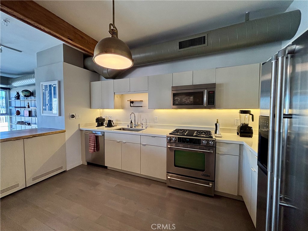 527 Molino Street, Unit 401 Los Angeles, CA 90013 - Photo 5 of 31 a kitchen with stainless steel appliances granite countertop a stove and a refrigerator
