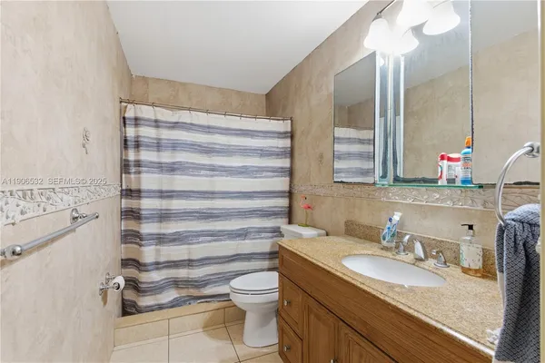 a bathroom with a granite countertop sink vanity mirror and toilet