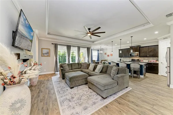 a living room with furniture kitchen view and a wooden floor