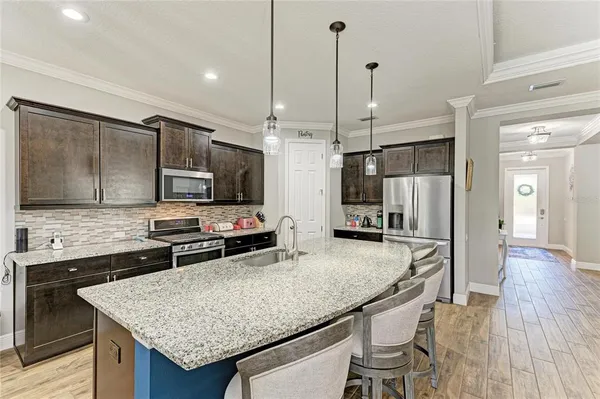 a kitchen with granite countertop kitchen island stainless steel appliances a sink stove and refrigerator