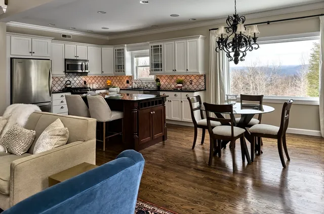 a kitchen with stainless steel appliances granite countertop a table chairs microwave and sink