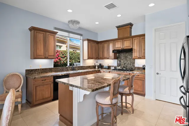 a large kitchen with stainless steel appliances granite countertop a large counter top a stove and a refrigerator