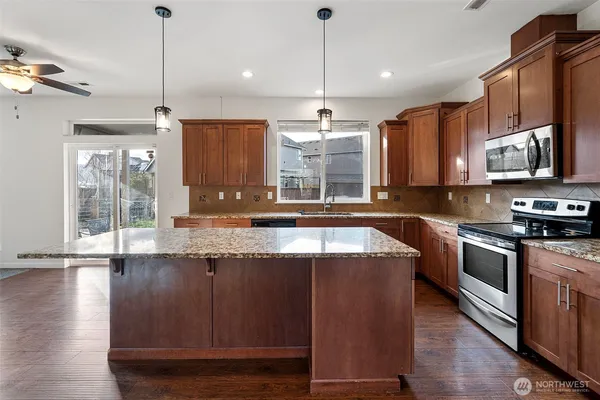 a kitchen with stainless steel appliances granite countertop a sink a stove and a wooden floors