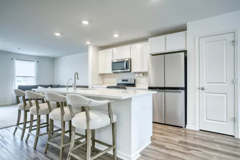 a kitchen with stainless steel appliances granite countertop a dining table chairs refrigerator and microwave