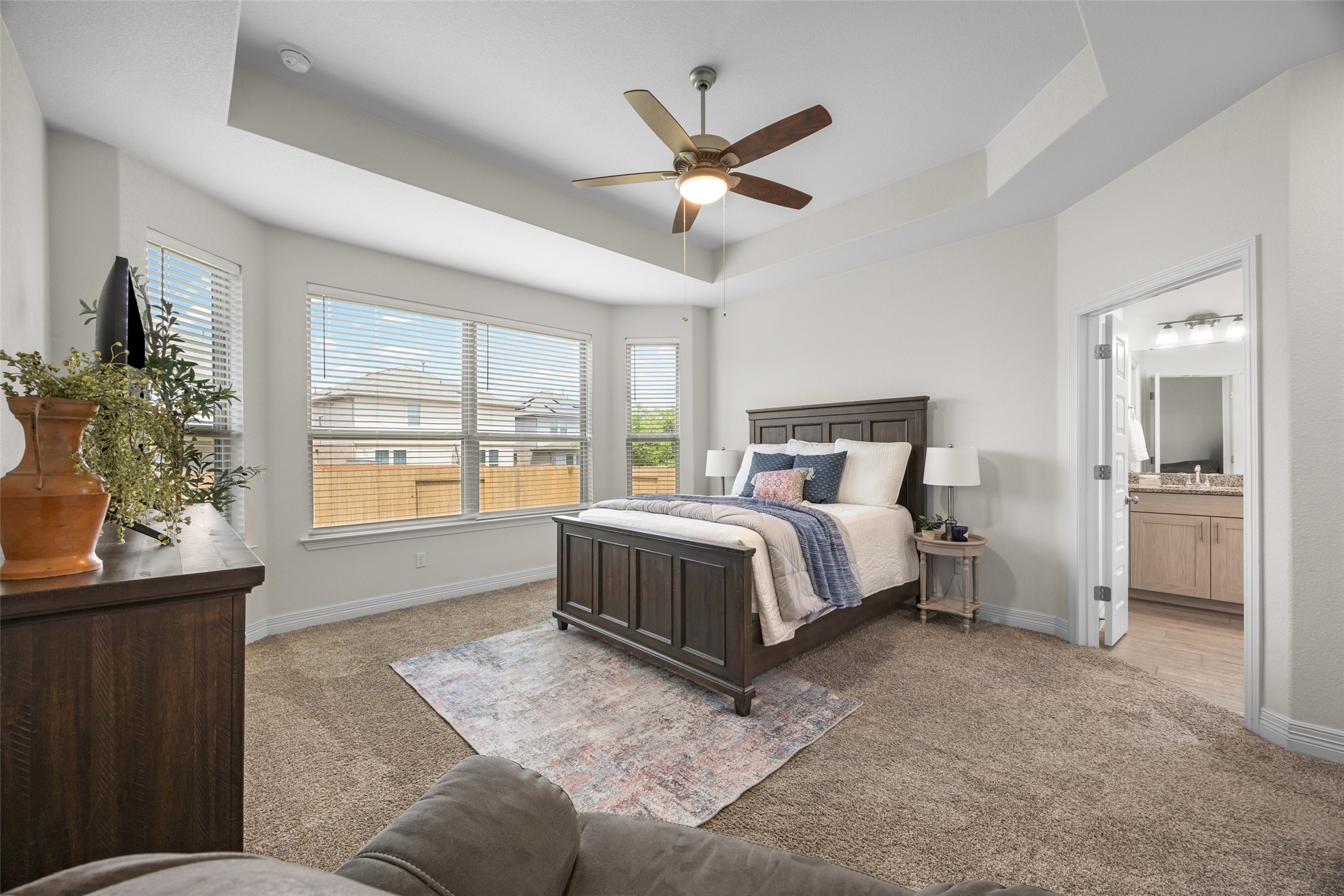 704 Muster Bend Georgetown, TX 78626 - Photo 17 of 38 Bedroom featuring light colored carpet, a raised ceiling, a ceiling fan, and connected bathroom