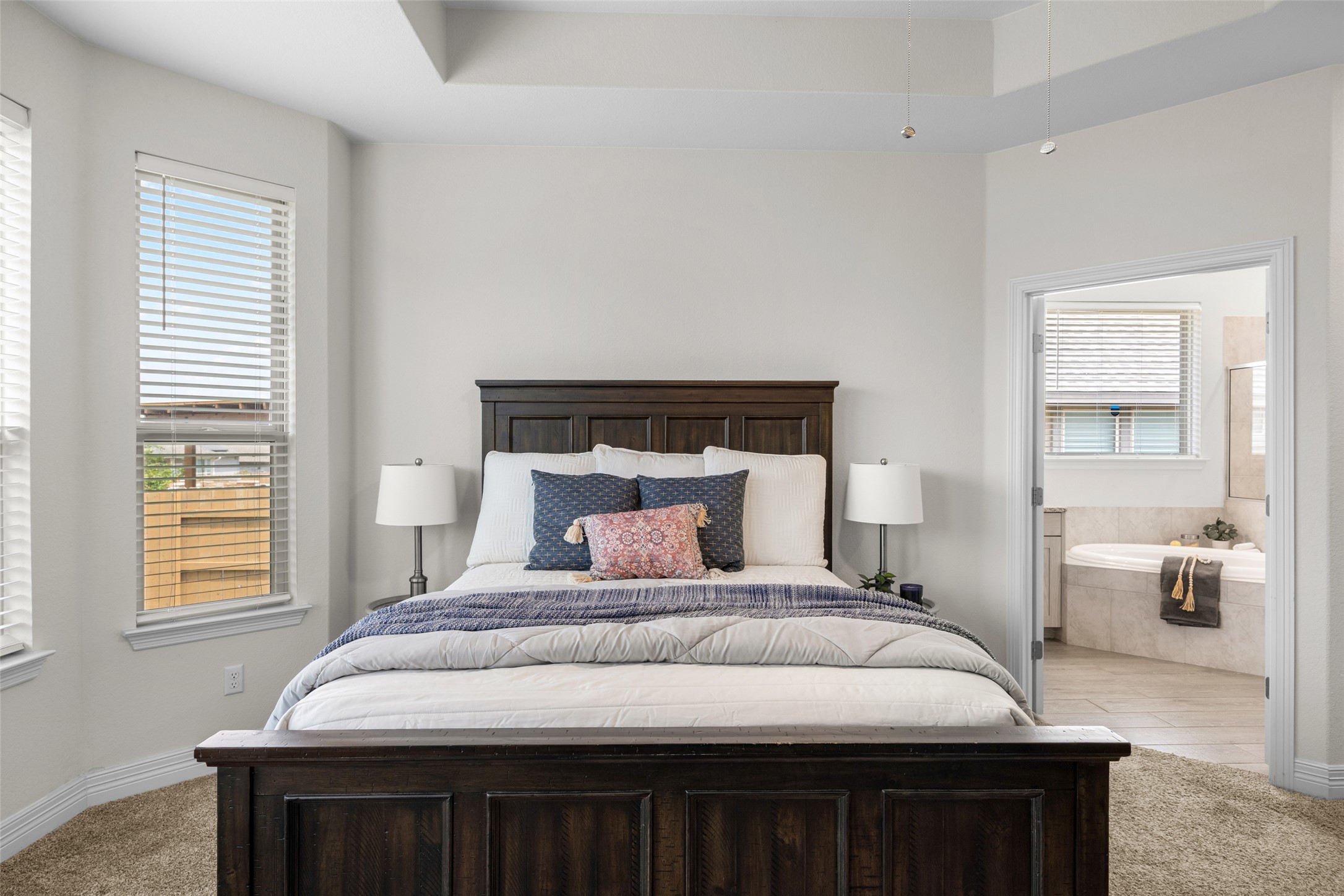 704 Muster Bend Georgetown, TX 78626 - Photo 19 of 38 Bedroom with light colored carpet, ensuite bath, and a raised ceiling