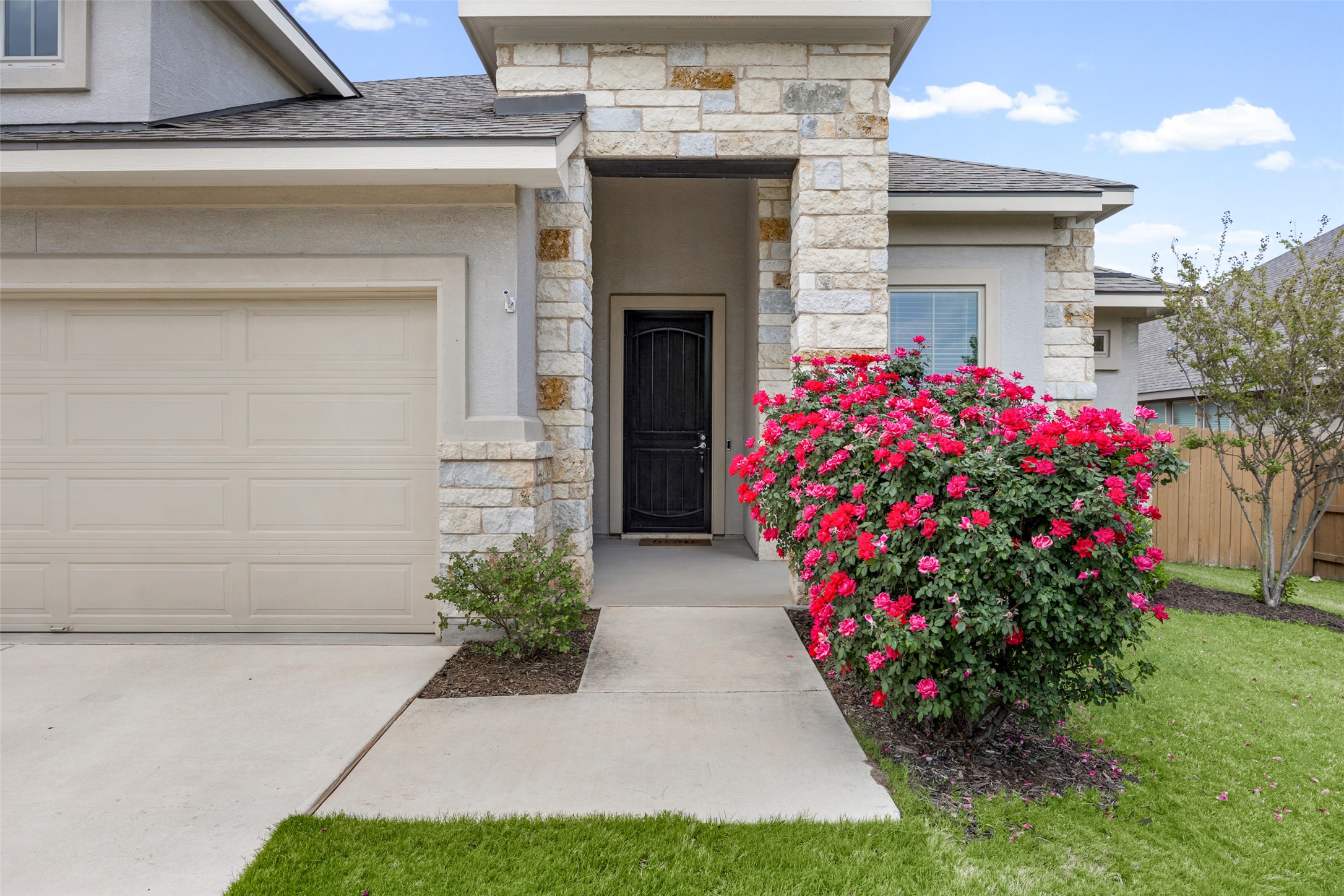 704 Muster Bend Georgetown, TX 78626 - Photo 2 of 38 View of exterior entry with stone siding, an attached garage, stucco siding, a shingled roof, and driveway