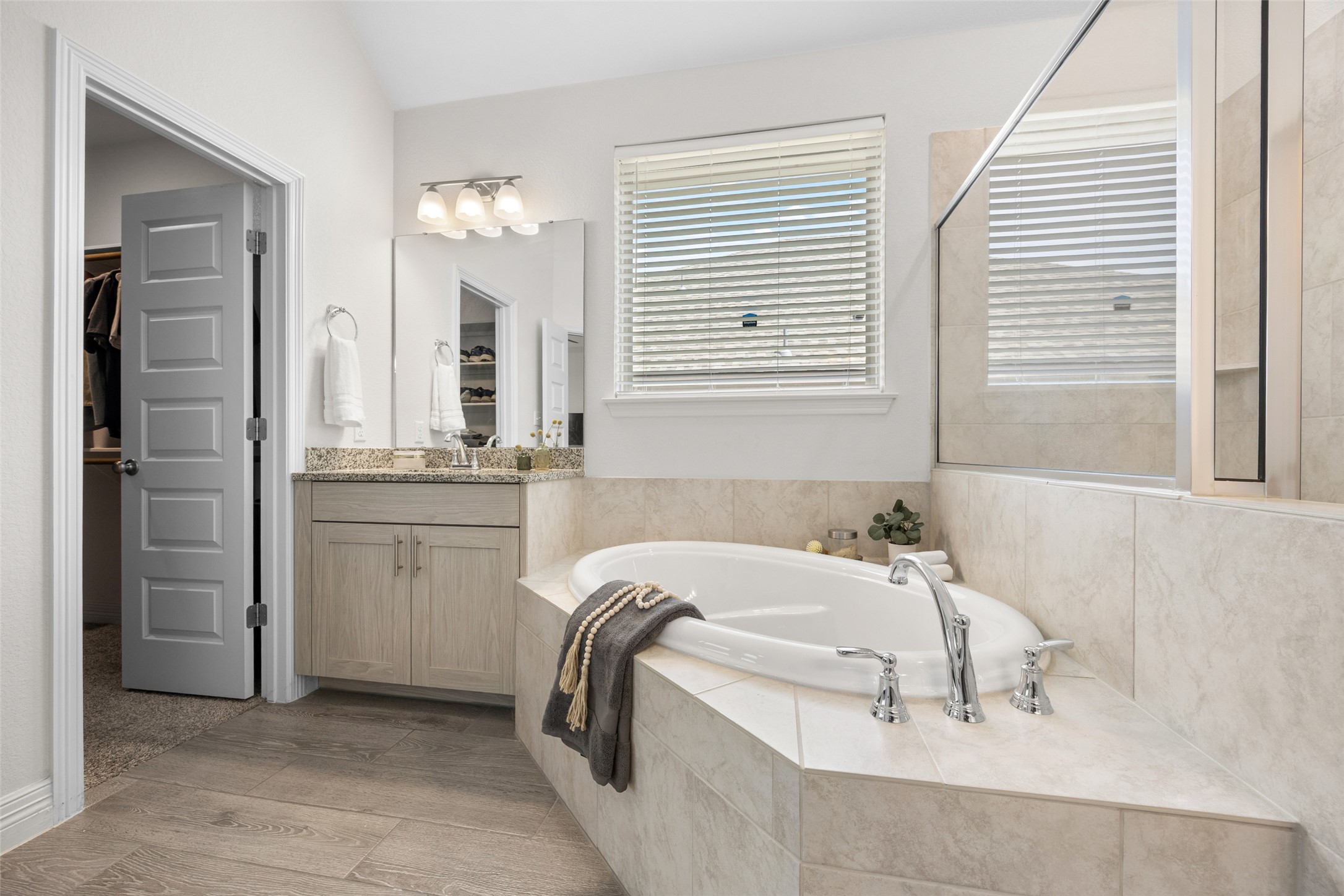704 Muster Bend Georgetown, TX 78626 - Photo 22 of 39 Bathroom featuring a bath, vanity, a walk in closet, lofted ceiling, and a tile shower