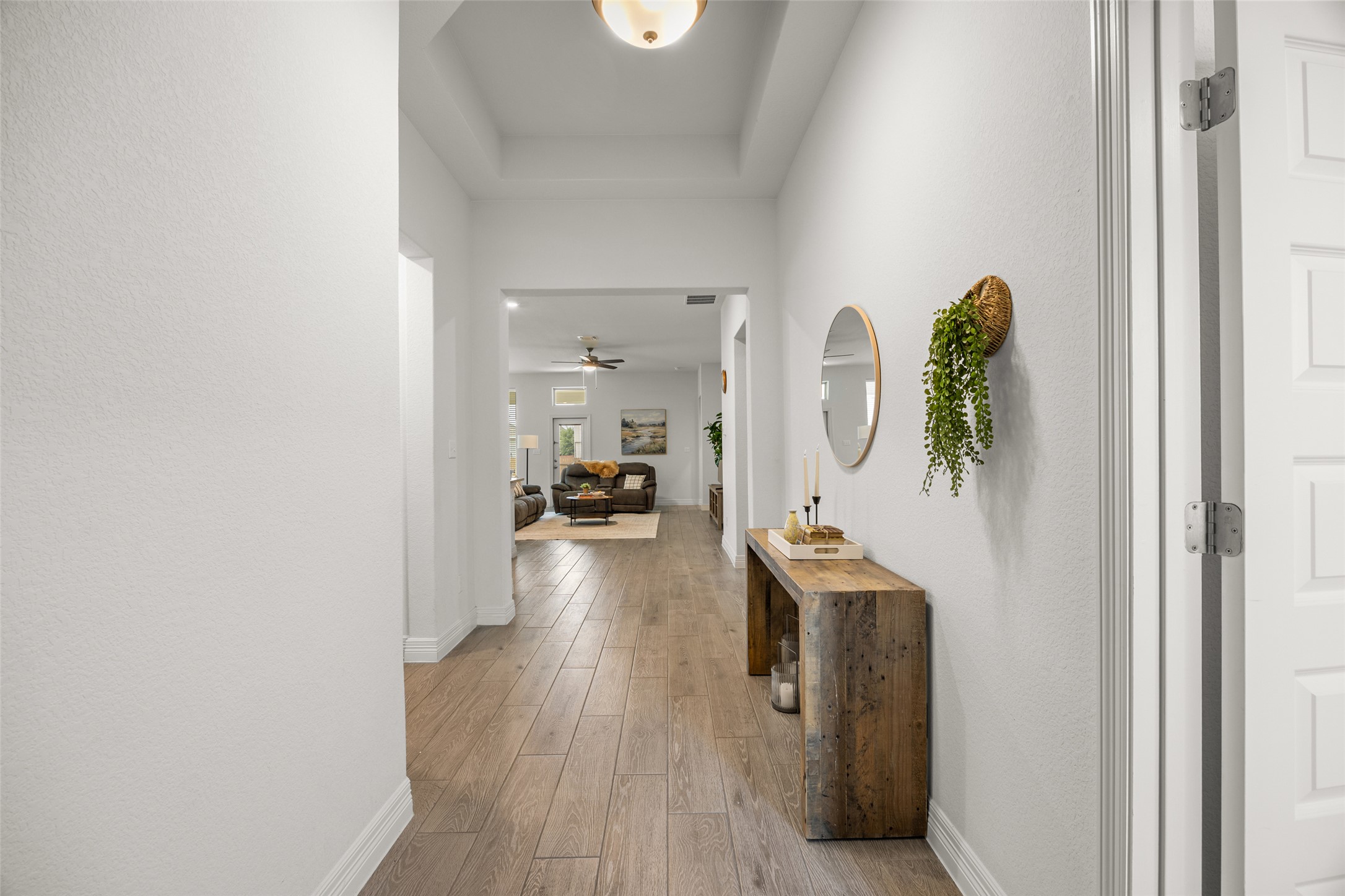 704 Muster Bend Georgetown, TX 78626 - Photo 4 of 39 Corridor featuring light wood-style floors and a raised ceiling