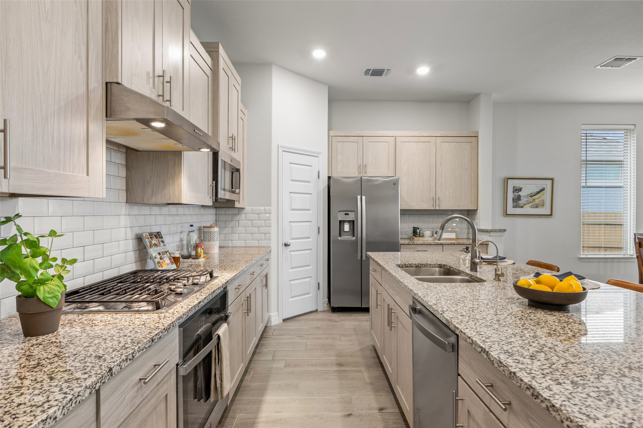 704 Muster Bend Georgetown, TX 78626 - Photo 7 of 38 Kitchen with light stone counters, stainless steel appliances, light wood-type flooring, recessed lighting, and tasteful backsplash