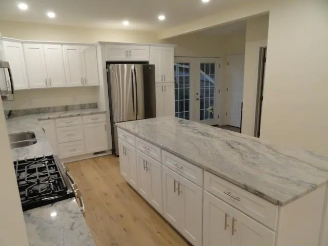 a kitchen with granite countertop a sink stove and refrigerator