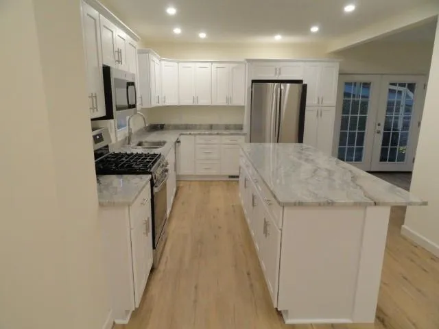 a kitchen with stainless steel appliances granite countertop a refrigerator a stove and a sink