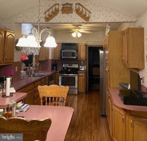 a kitchen with stainless steel appliances granite countertop a sink dishwasher stove and refrigerator with wooden floor