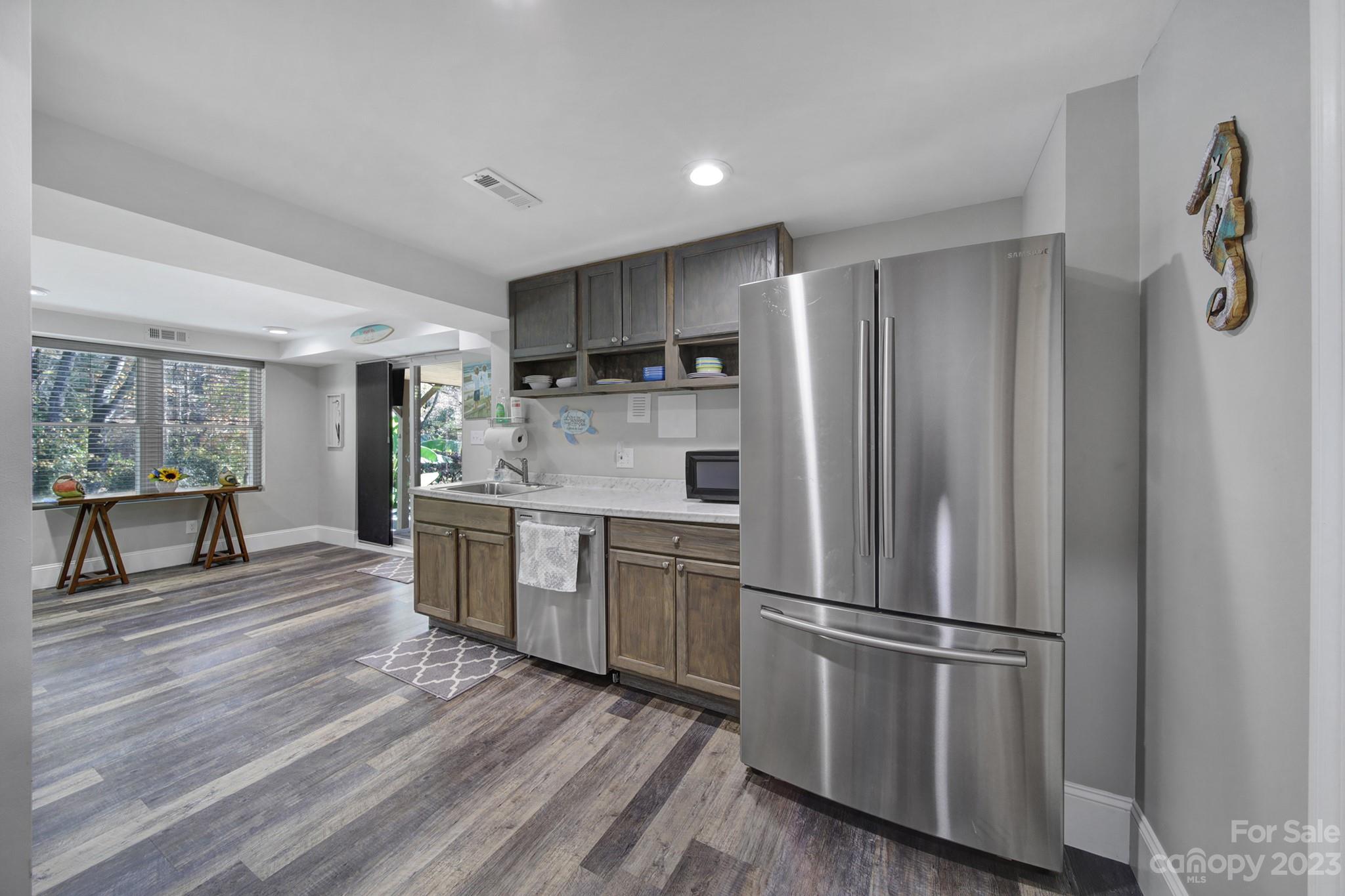 4028 Windward Drive Tega Cay, SC 29708 - Photo 32 of 48 a kitchen with a refrigerator a sink dishwasher a stove and white cabinets with wooden floor