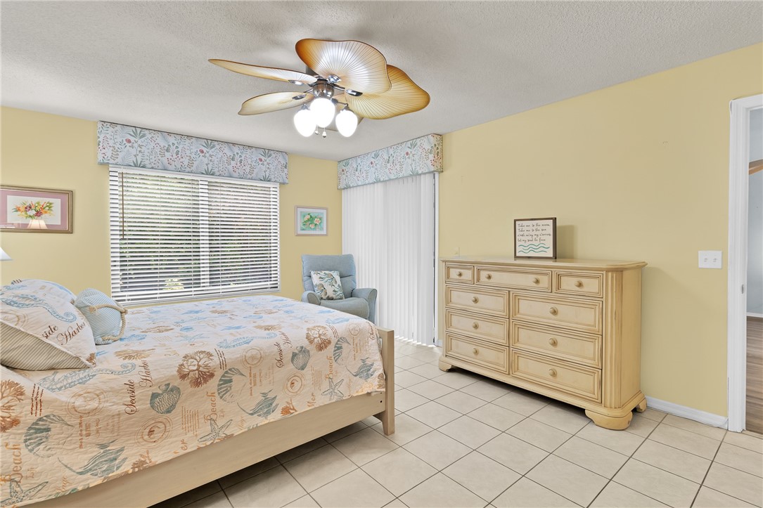 9645 Estuary Way, Unit 1 Sebastian, FL 32958 - Photo 14 of 36 a bedroom with a bed a chandelier and a dresser