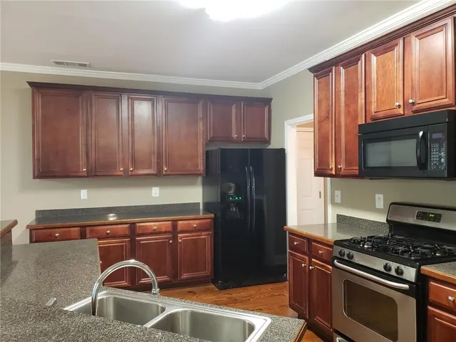 a kitchen with granite countertop wooden cabinets and a stove top oven