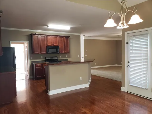 a kitchen with stainless steel appliances granite countertop a stove top oven a refrigerator and a dining table with wooden floor