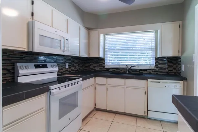 a kitchen with granite countertop white cabinets and white appliances