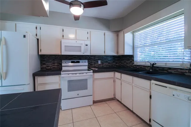 a kitchen with granite countertop white cabinets and white appliances