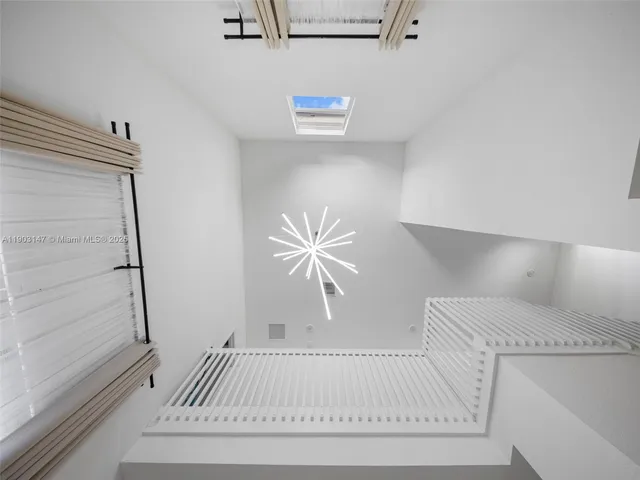 a large white kitchen with a white countertops a stove a couch and a dining table with wooden floor