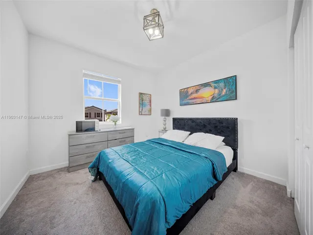 a spacious bedroom with a bed couch chandelier and a window