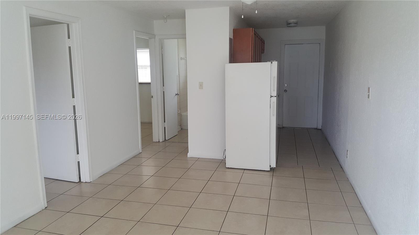 237 Southwest 5th Street Deerfield Beach, FL 33441 - Photo 3 of 11 a view of a refrigerator in kitchen and an empty room in wooden floor