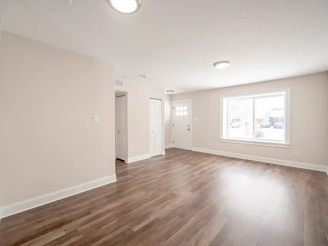 an empty room with wooden floor and window