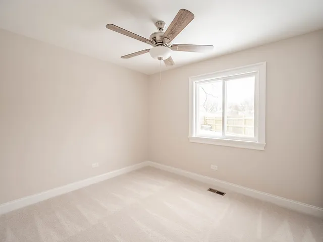an empty room with a window and a ceiling fan