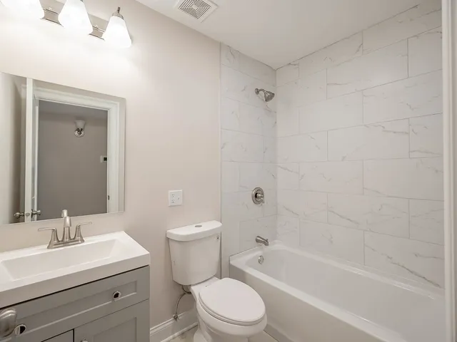 a bathroom with a toilet a sink a mirror and bathtub