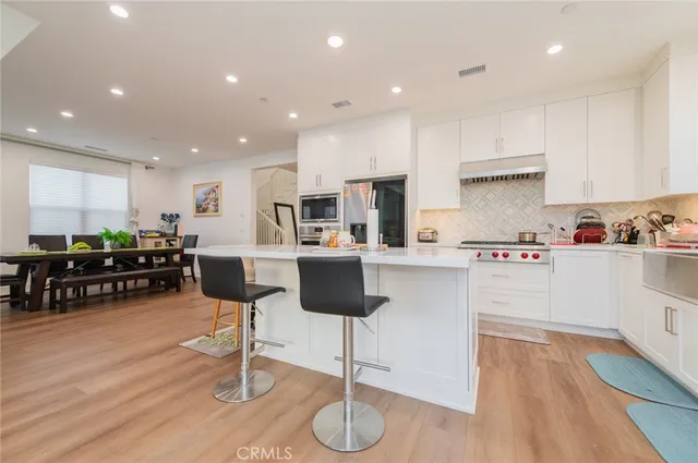 a kitchen with stainless steel appliances kitchen island granite countertop white cabinets and wooden floor