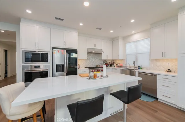 a kitchen with a sink a stove a refrigerator and white cabinets with wooden floor