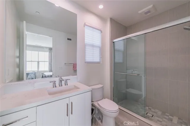 a bathroom with a shower sink vanity mirror and toilet