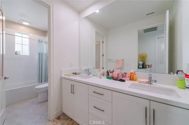 a bathroom with a double vanity sink toilet and shower