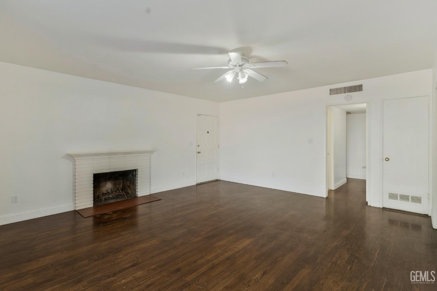 Undisclosed Address Bakersfield, CA 93304 - Photo 6 of 21 an empty room with wooden floor fireplace and ceiling fan