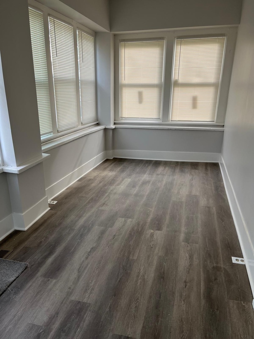 11578 South Perry Avenue Chicago, IL 60628 - Photo 2 of 11 an empty room with wooden floor and windows