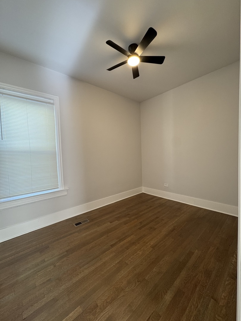 11578 South Perry Avenue Chicago, IL 60628 - Photo 4 of 11 an empty room with wooden floor and windows