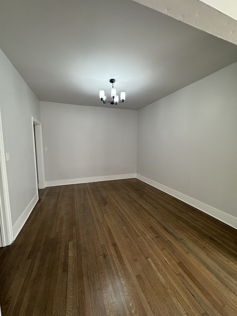 11578 South Perry Avenue Chicago, IL 60628 - Photo 6 of 11 an empty room with wooden floor chandelier fan and windows