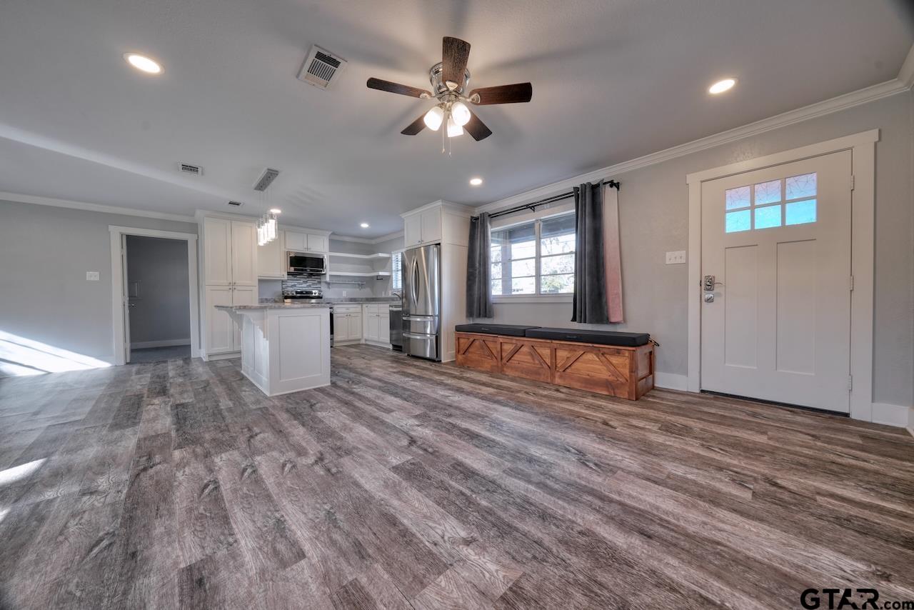a living room with stainless steel appliances kitchen island furniture and a ceiling fan